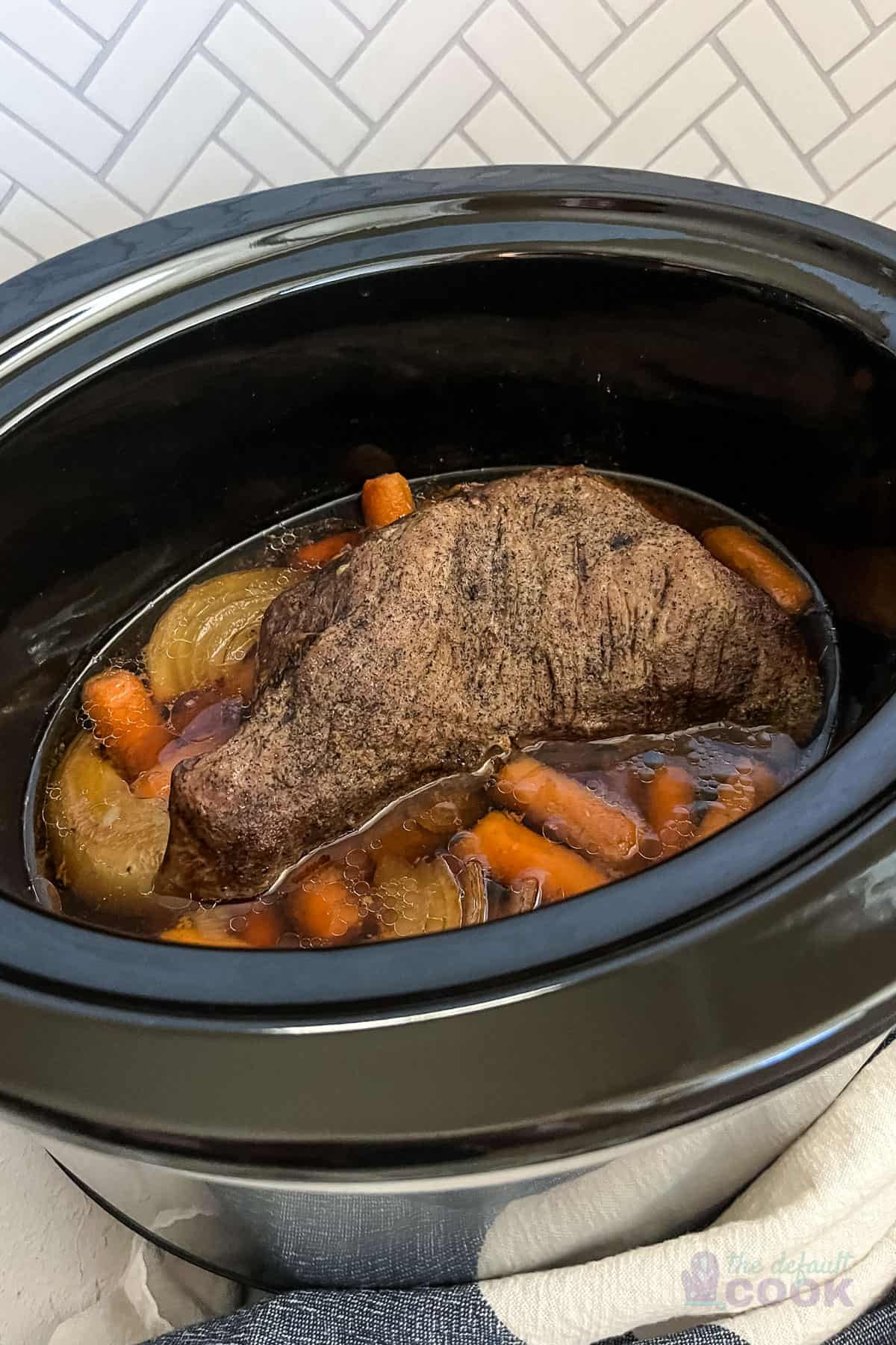 Cooked roast with carrots and onions in a crock pot.