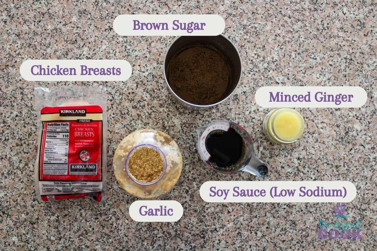 Labeled ingredients on a kitchen counter: chicken breasts, brown sugar, minced ginger, soy sauce, and garlic.