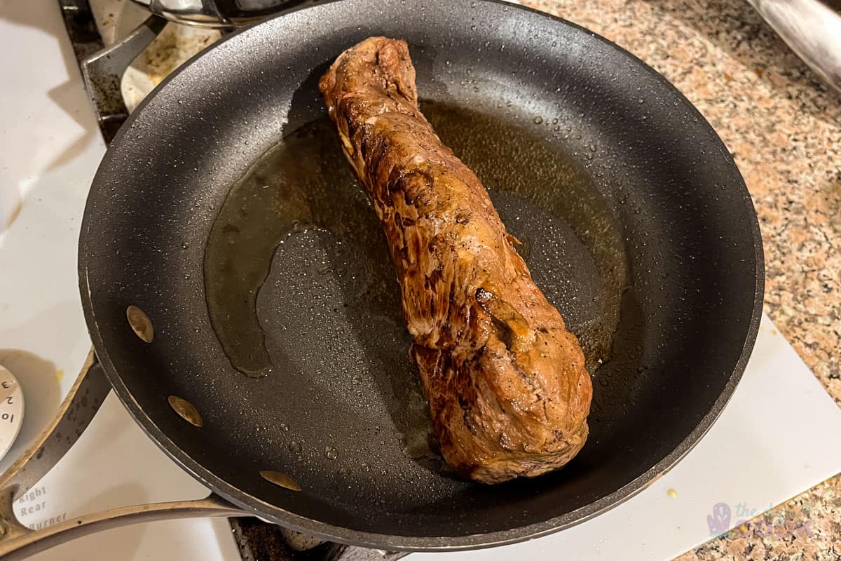 Searing pork in a pan on the stove.