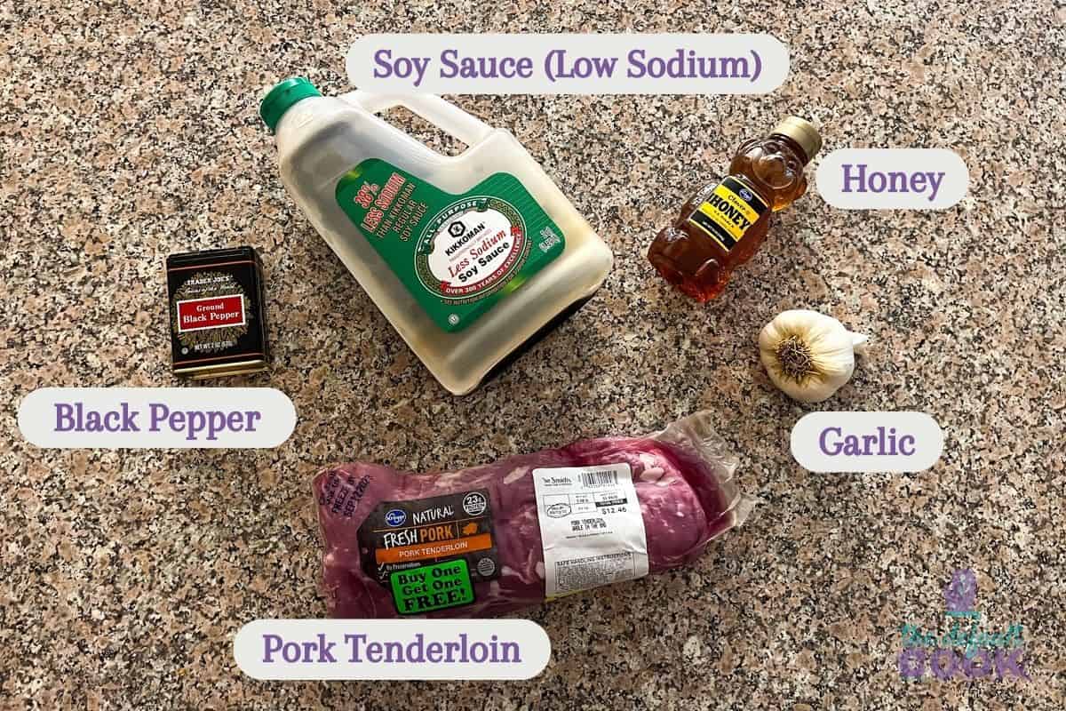 Labeled ingredients on a kitchen counter: low sodium soy sauce, honey, garlic, black pepper, and pork tenderloin.
