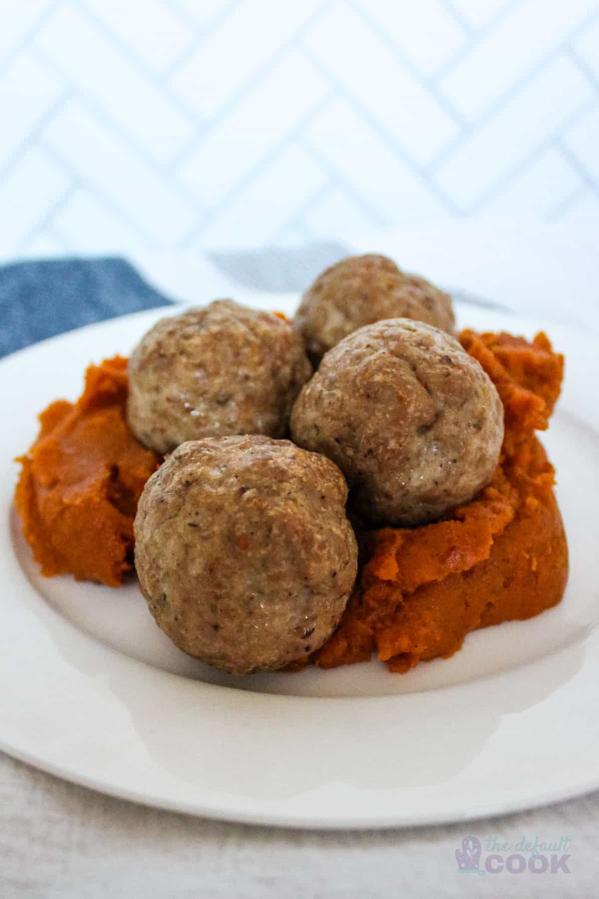 4 baked pork meatballs on a bed of mashed sweet potatoes.