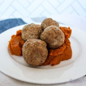 4 baked pork meatballs on a bed of mashed sweet potatoes.