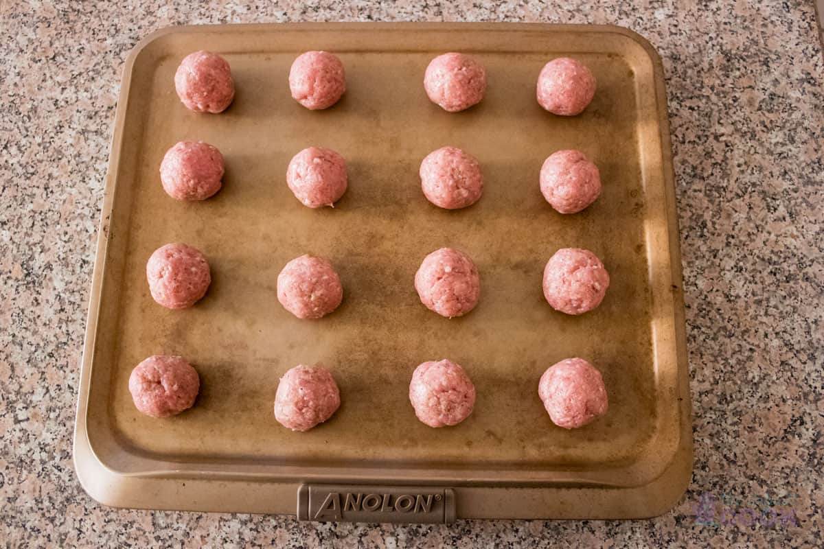 16 meatballs on a nonstick baking sheet.