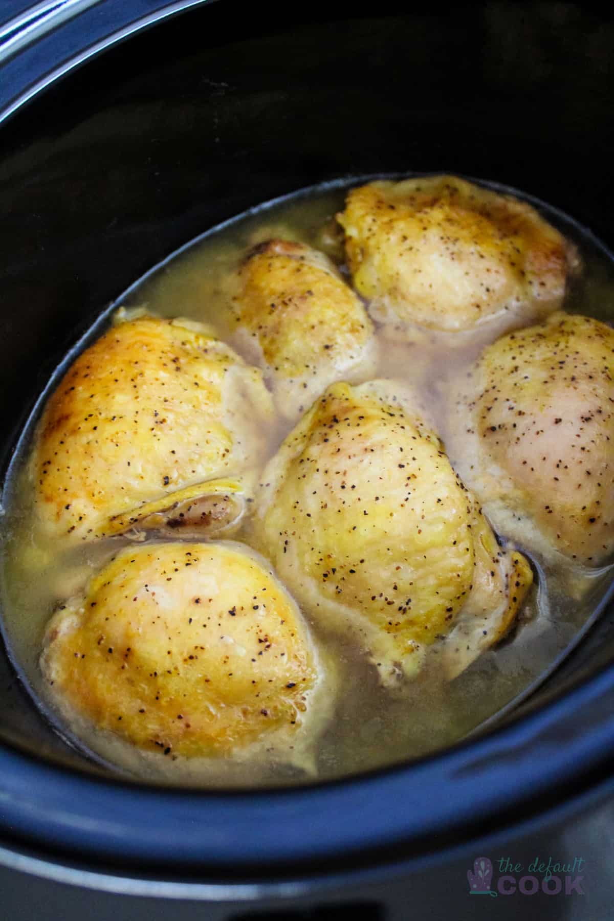 6 cooked chicken thighs in an oval slow cooker.