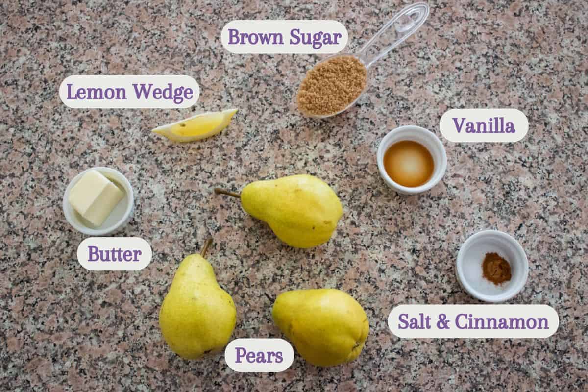 Three pears, a lemon wedge, butter, brown sugar, vanilla, and a small bowl of salt and cinnamon are arranged on a speckled countertop, each labeled with white tags and purple text.