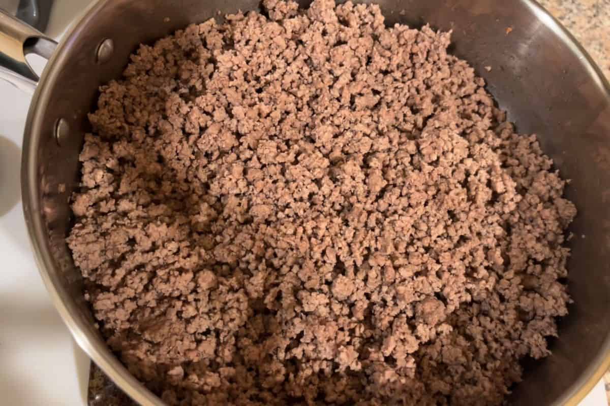 A pot filled with cooked ground beef, with small crumbles of meat evenly distributed, seen from above on a stovetop.