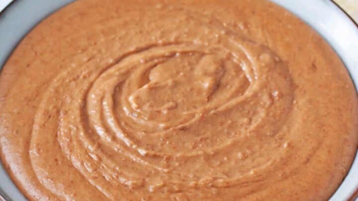 A bowl filled with creamy, smooth refried beans, with a few tortilla chips visible in the background.